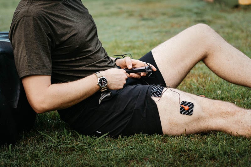 Athlete using wired electric muscle stimulator on leg