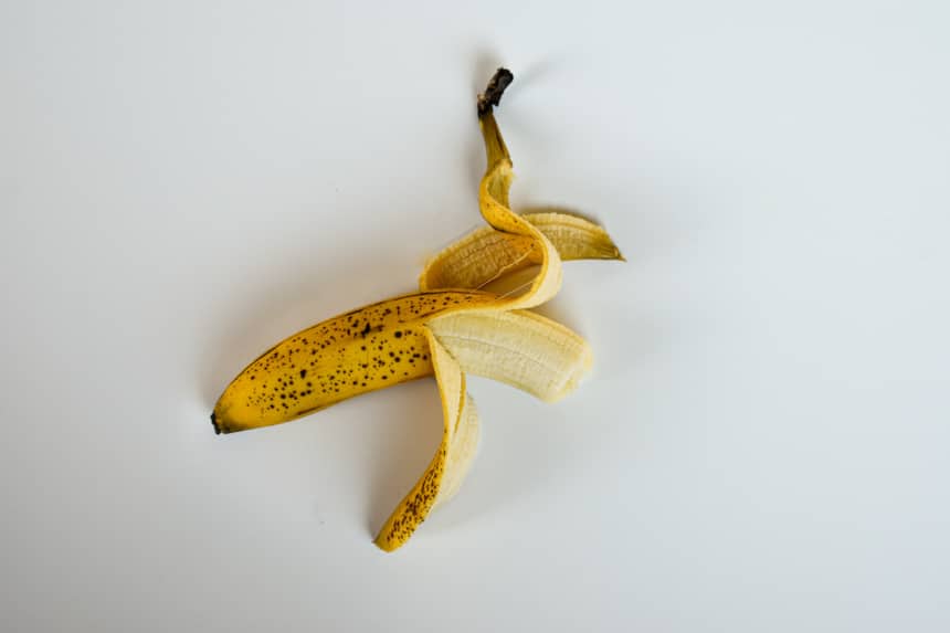 Bruised Banana Half Unpeeled on White Background