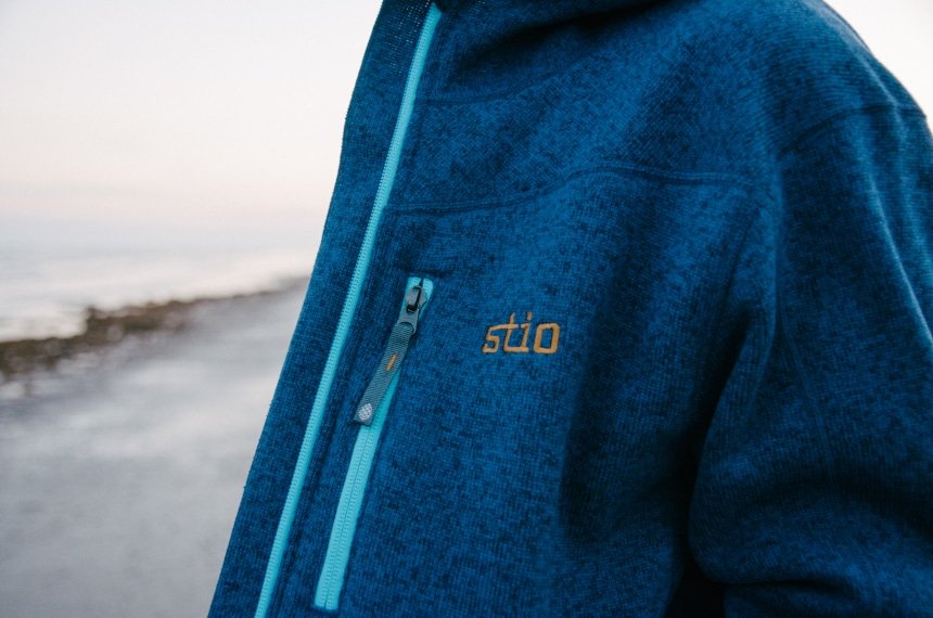 Close Up of Stio Logo on Wilcox Fleece Hoodie in Larkspur Blue on Model