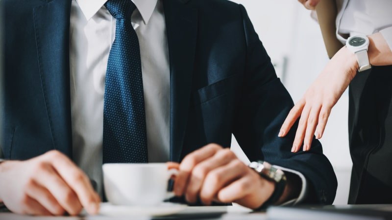 Female Coworker Brushing Up Against Man in Suit and Tie