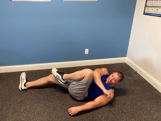 Fitness model performing bicycle crunch indoors