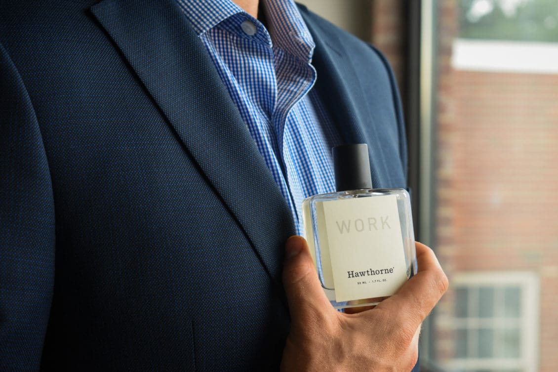 Male Model Wearing Blue Suit With Blue Check Shirt And Holding Hawthorne Work Fragrance Side Angle