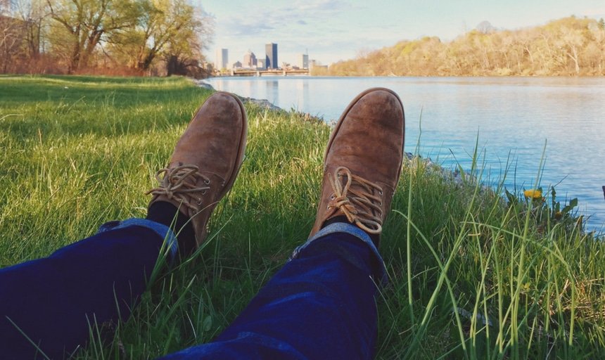 Man sitting on the edge of the water with his feet in the shot