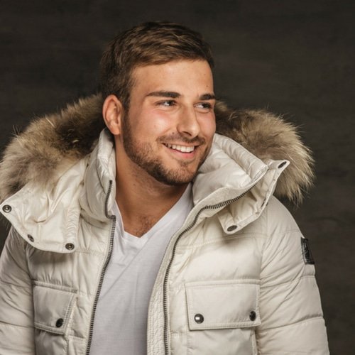 man with round face and close beard with a bomber jacket and smiling