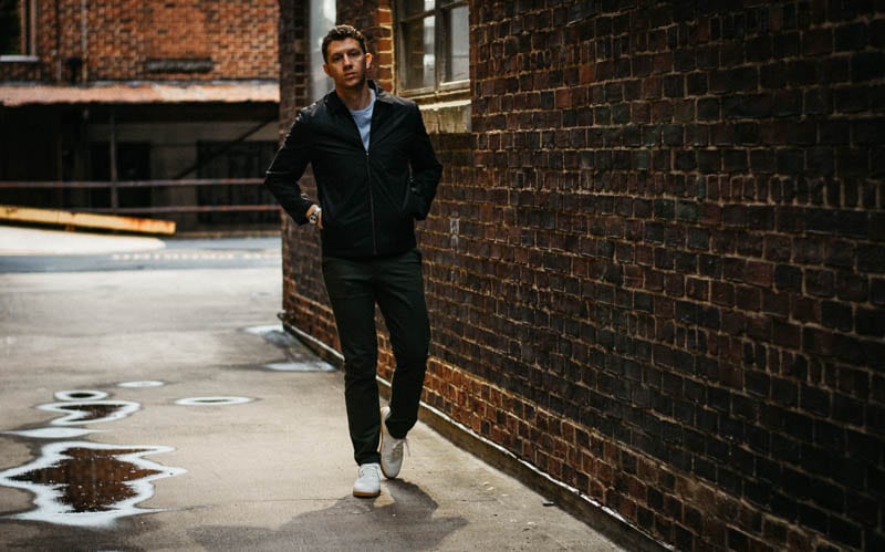 model in alley against brick wall wearing full asket outfit