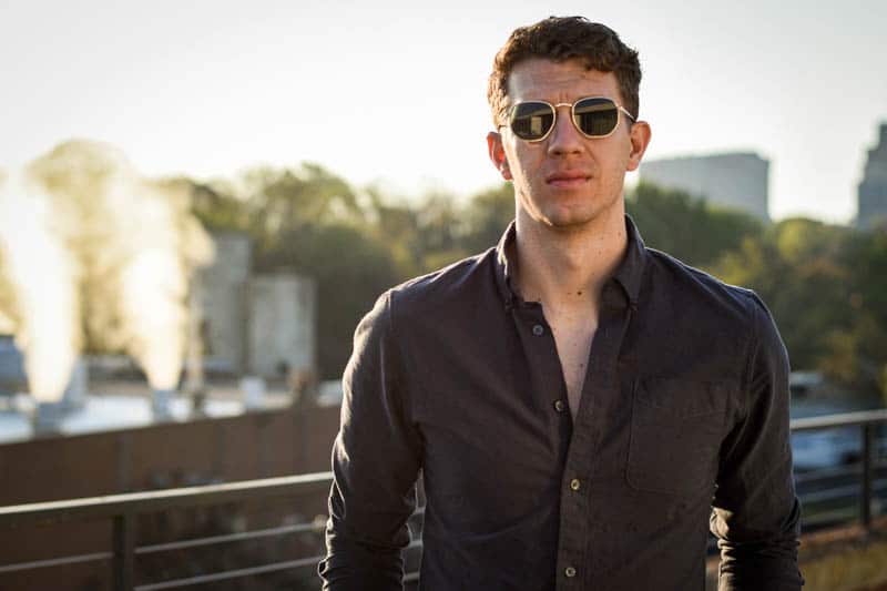 model in gold framed sunglasses with factory in background