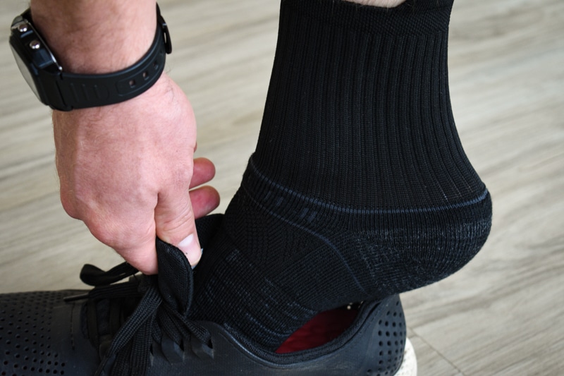 model putting on shoe wearing black strideline mid sock