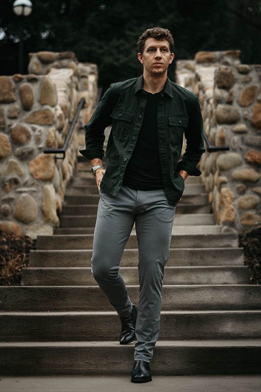 model wearing grey chinos and black ace marks troy chelsea boots with green shirt