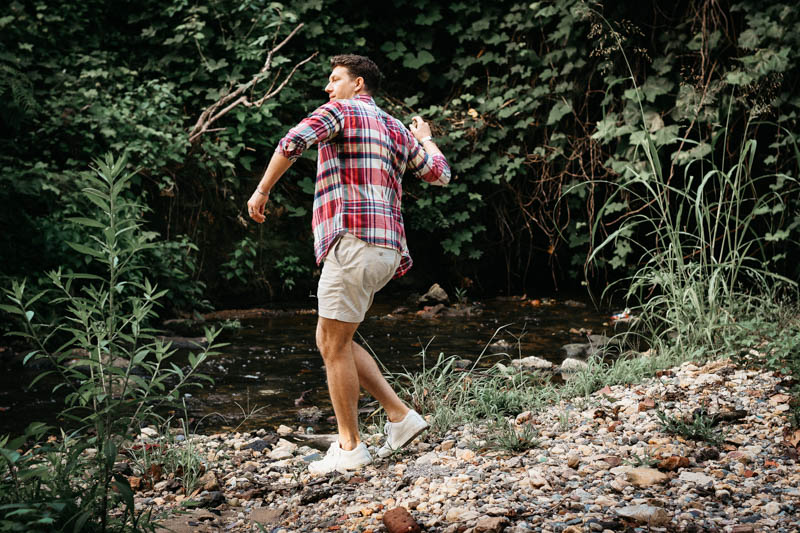 model wearing j crew button shirt and dock shorts skipping rocks by rier