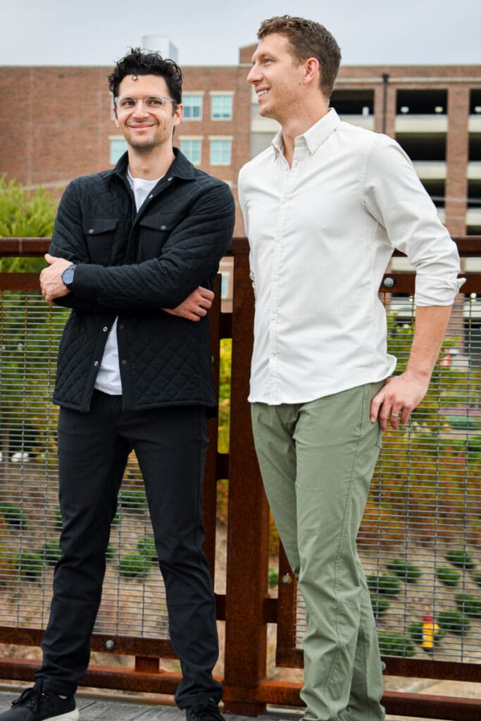 two models smiling against railing